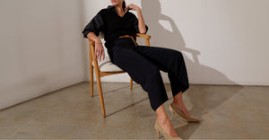 Women slouch in a chair in a black jumpsuit