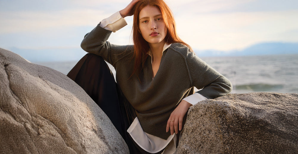 women posed leaning on a rock on the beach